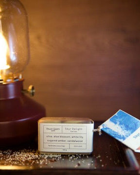 Vintage-style light bulb in a glass enclosure and soap on a wooden surface with a blurred background