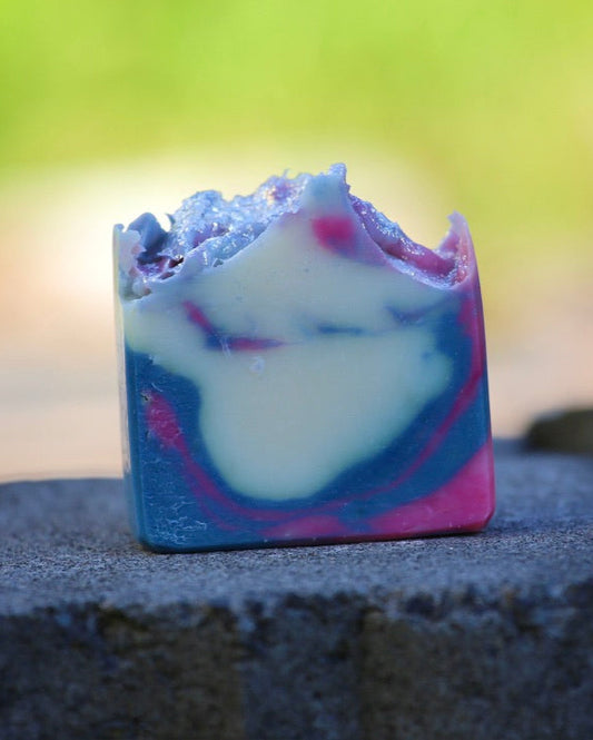 Colorful soap bar on a dark stone surface with a blurred natural background
