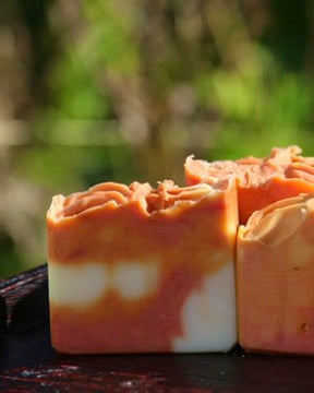 Close-up of a soap bar with a orange and white marbled design on a blurred natural background