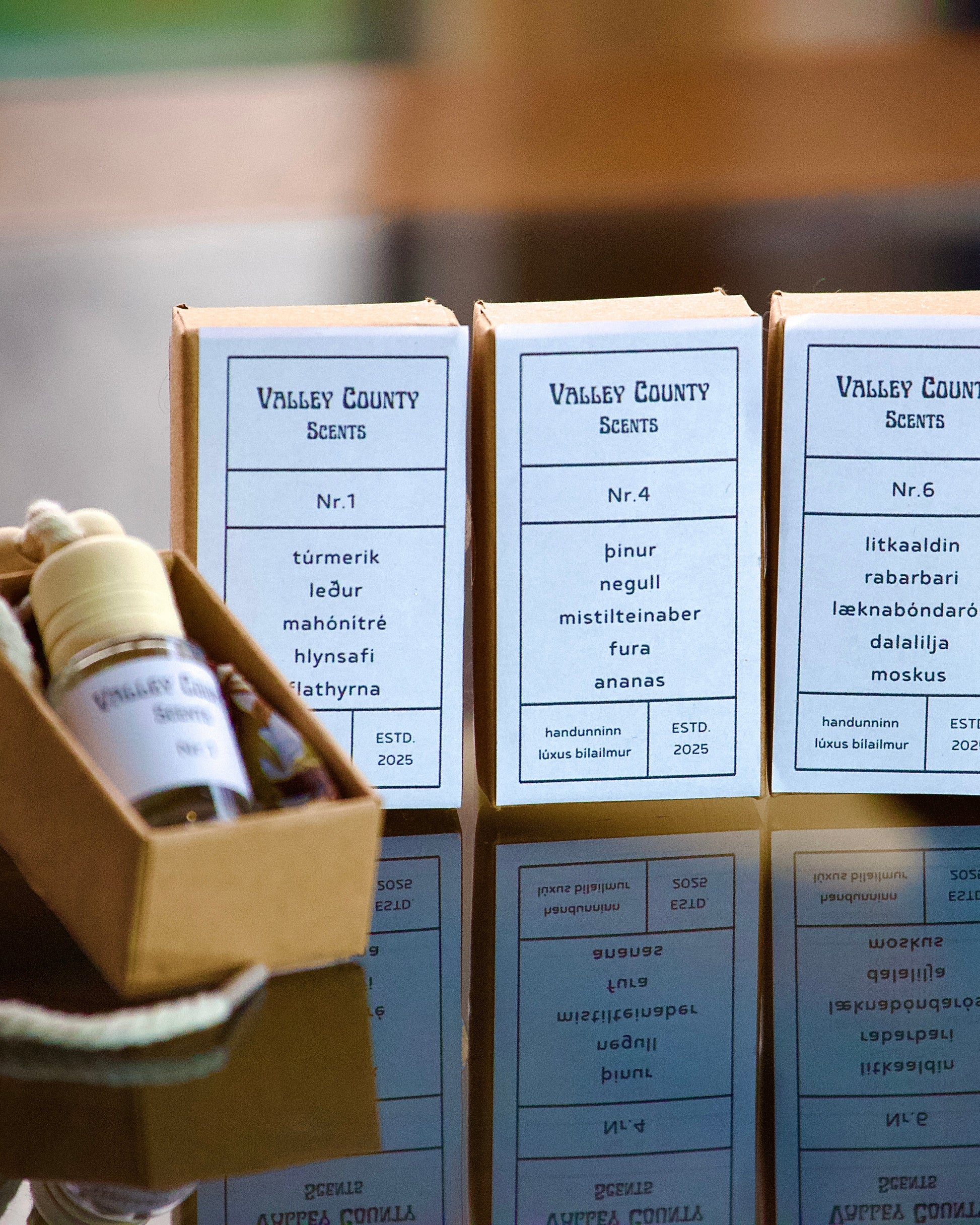 Valley County Scents car diffuser bottles and boxes on a reflective surface with a elegant background.