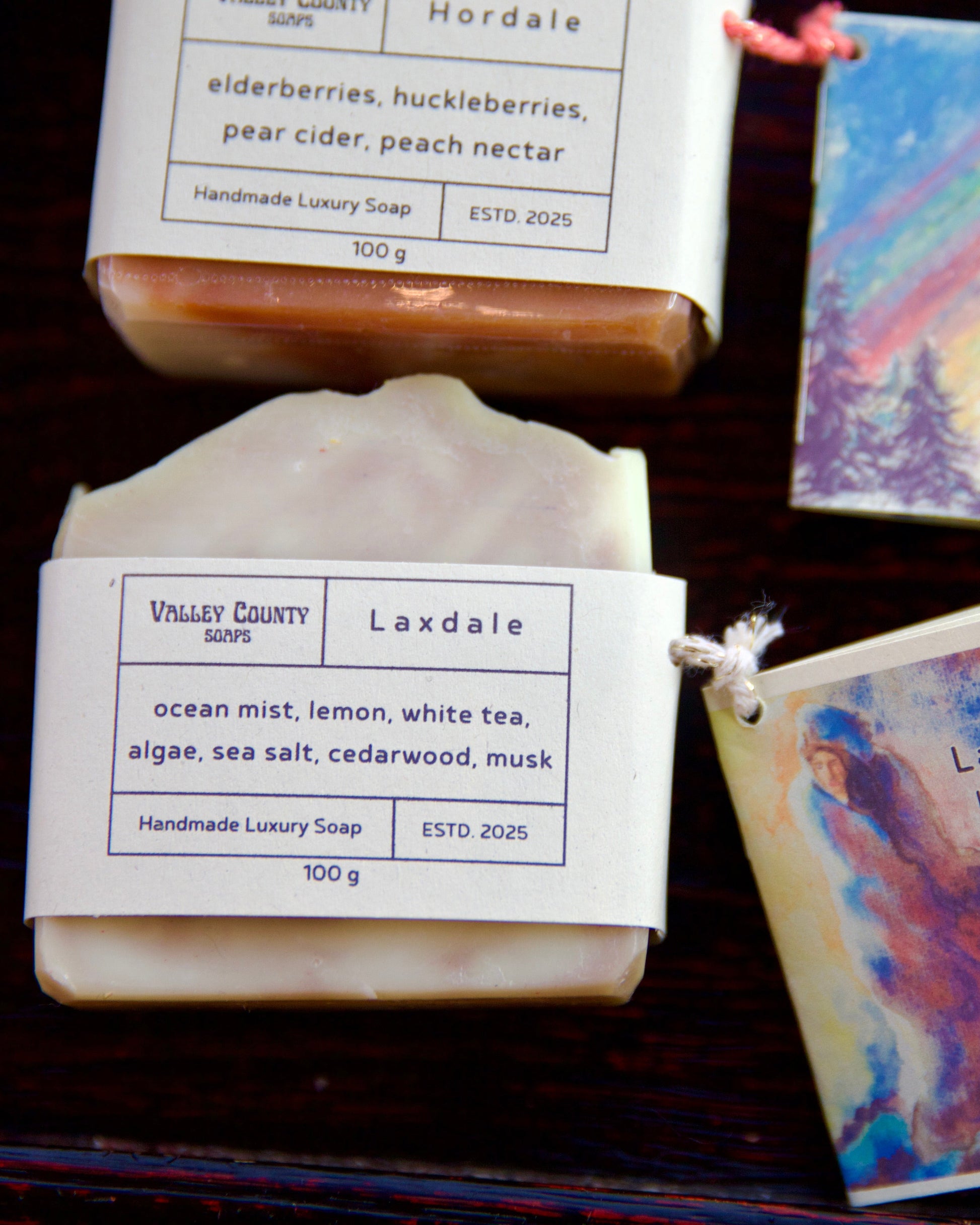 Handmade soap bars with labels and colorful packaging on a dark surface
