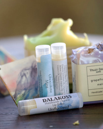 Dalakoss lip balm tubes and Valley County soap bars on a wooden surface with a blurred background