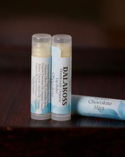 Three lip balm tubes with visible Dalakoss branding on a dark surface