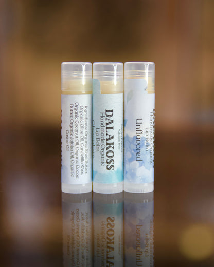 Three lip balm tubes with visible Dalakoss branding on a blurred background