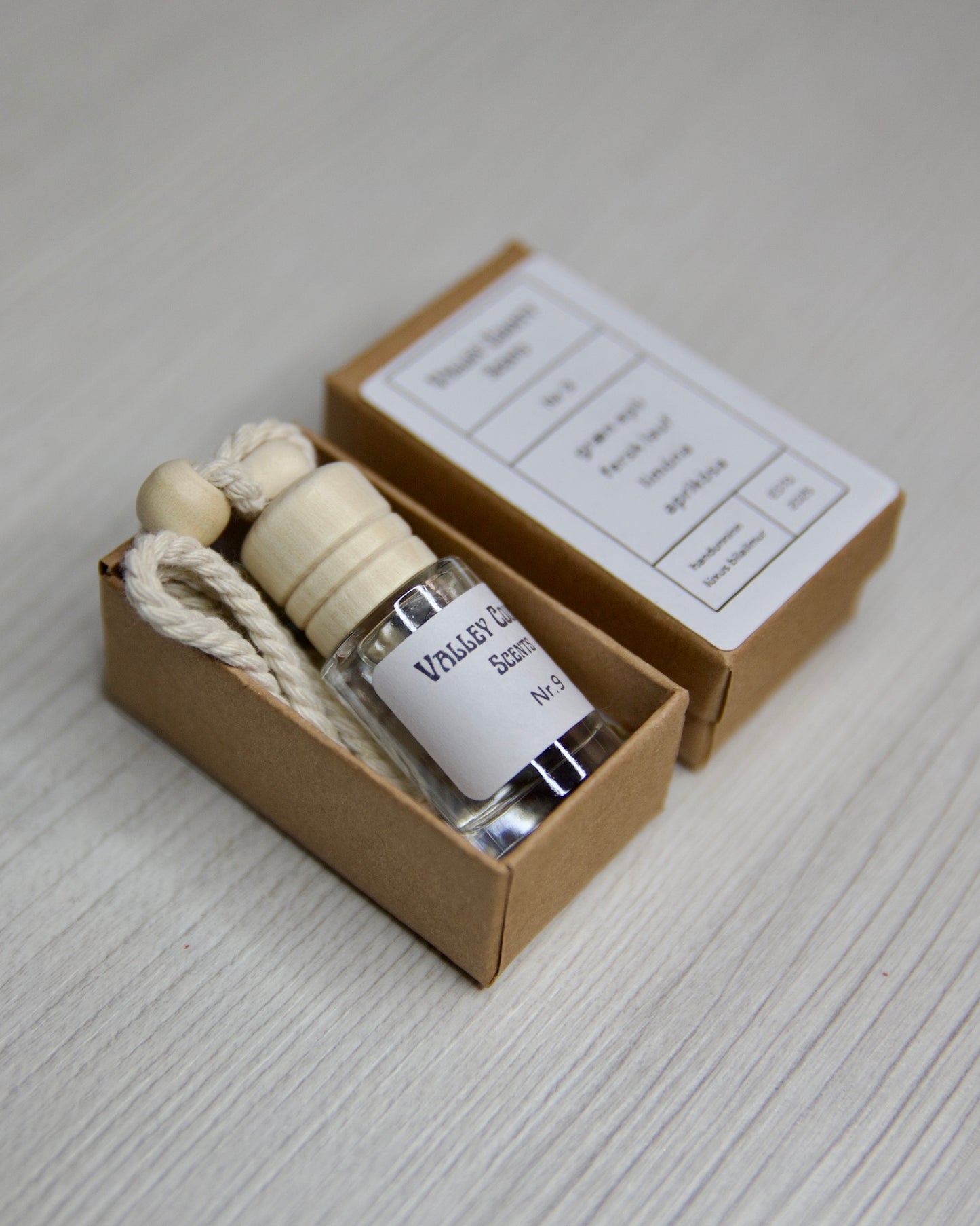Small glass bottle with a wooden cap in a elegant box on a light gray surface